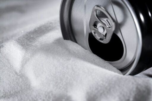 A soft drink can sitting on a bed of sugar. The WHO wants taxes raised on sugary drinks