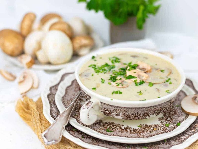 A bowl of mushroom soup garnished with chopped parsley.